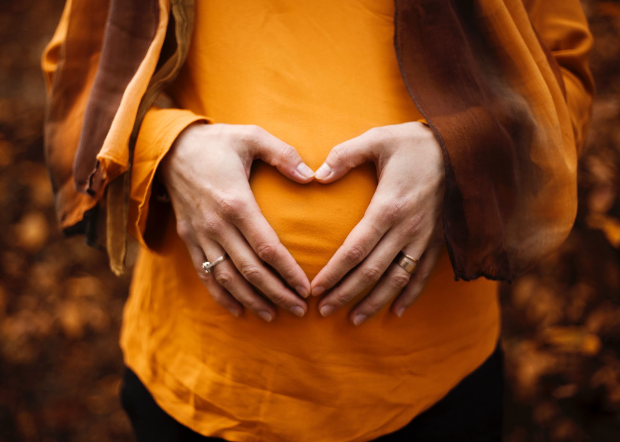 mujer embarazada con sus manos encima de la barriga formando un corazón