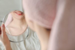 Mujer mirando su boca en el espejo para comprobar si tiene los dientes desgastados
