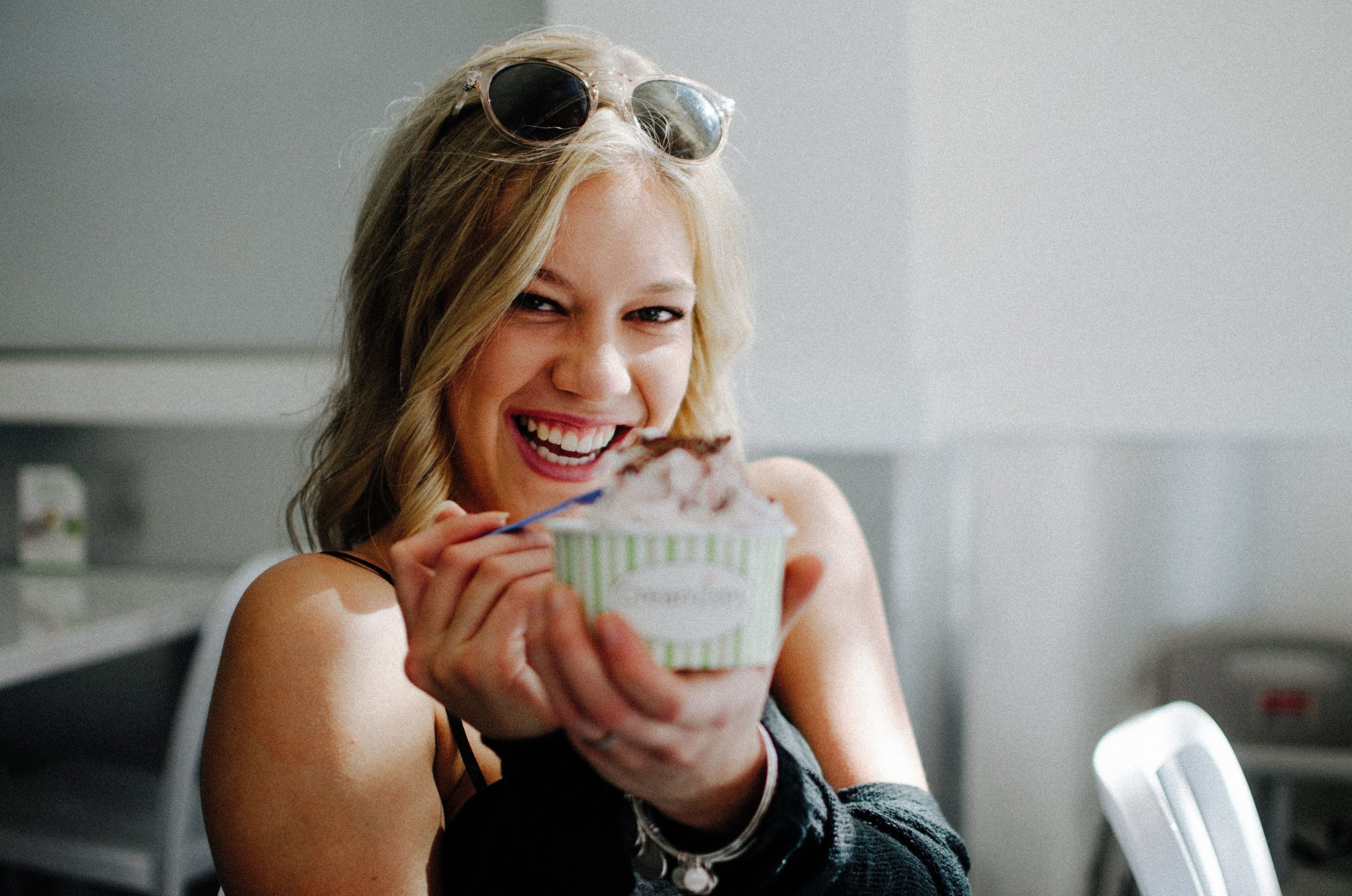 Una mujer muy sonriente comiendo un helado
